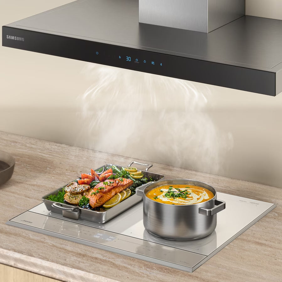 cooking food on an induction hob with its smoke sucked by chimney hood